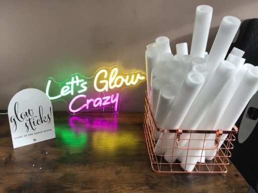 A neon sign reads "Let's Glow Crazy" next to a basket of white tubes.
